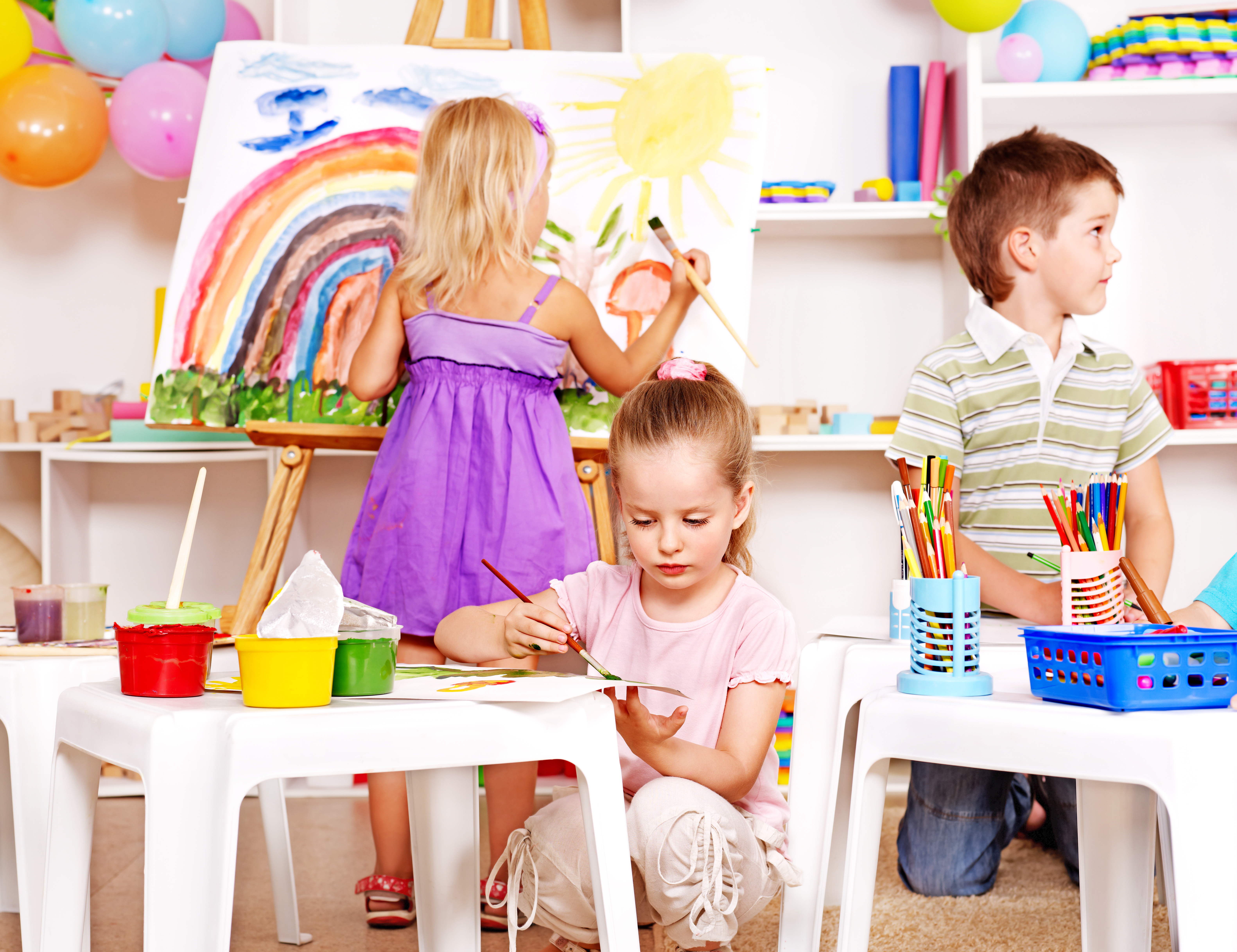Group children painting at easel in school.