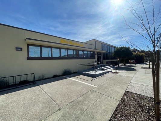 Modern building with large windows and accessible entrance, labeled "Alta Vista Restaurant," set against a clear blue sky, showcasing its inviting exterior.