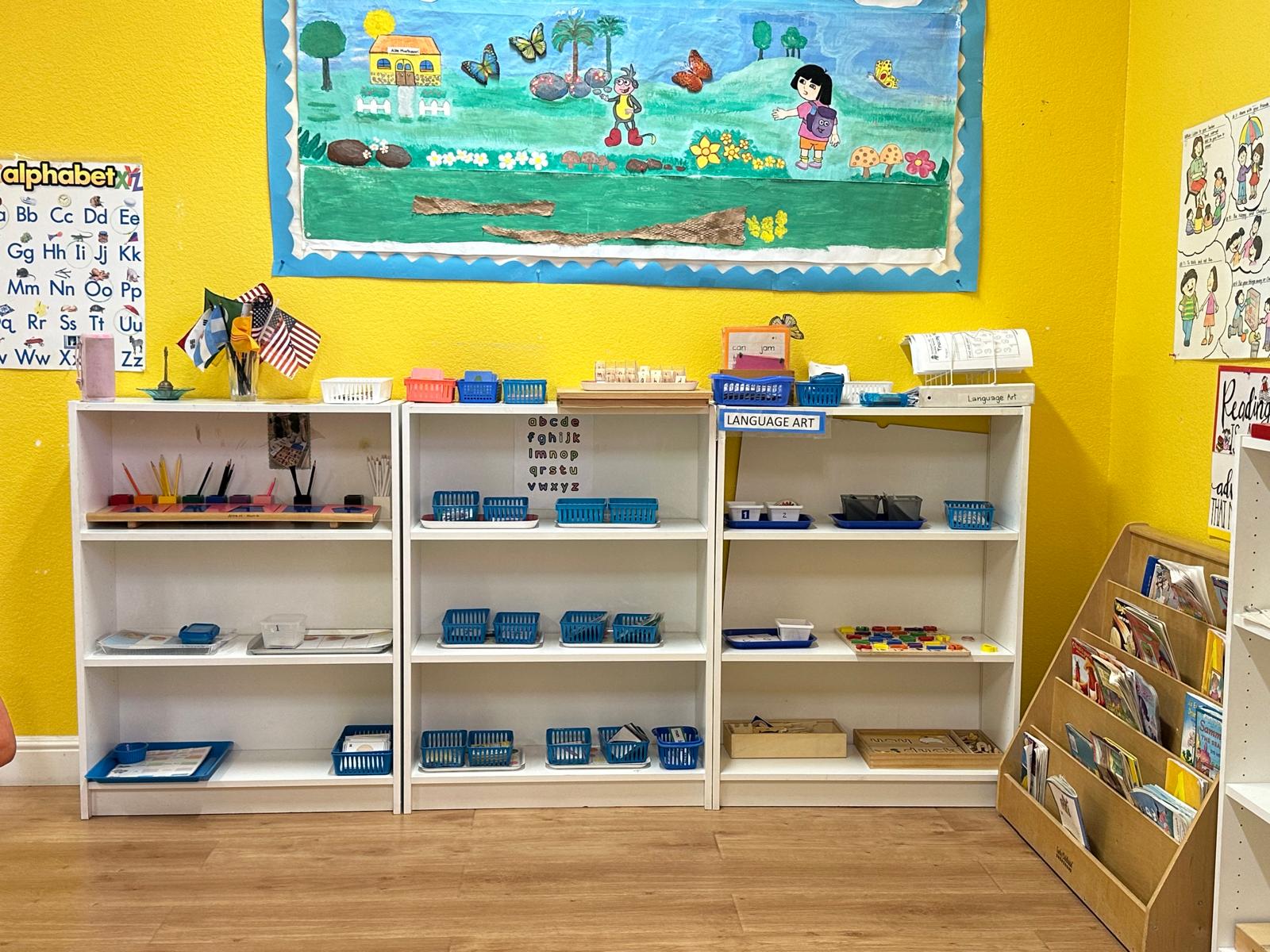 Bright classroom featuring organized shelves with educational materials, a vibrant mural, and a reading corner, promoting an engaging learning environment.